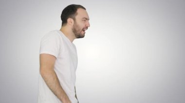 Beyaz tişörtlü, uykulu erkek. Arkaplanda yürürken gözlerini ovuşturuyor..