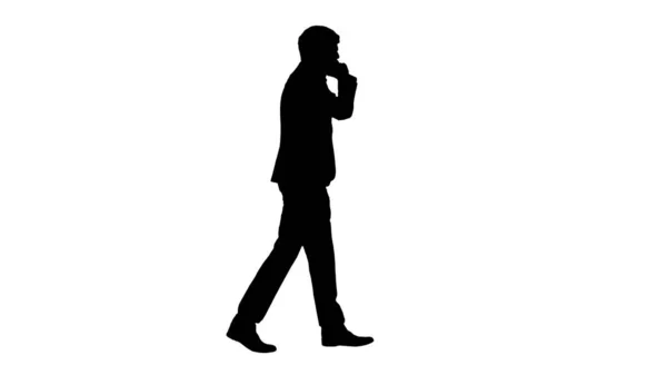 Силуэт Молодой бизнесмен разговаривает по телефону во время прогулки. — стоковое фото