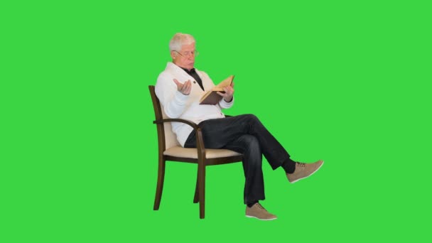 白发苍苍的老人正在阅读一本书，以便在绿色屏幕上拍照。. — 图库视频影像