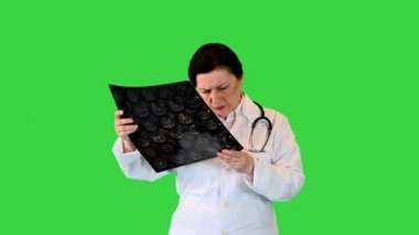 Olgun kadın doktor, yeşil ekranda yürürken MRI film taramalarını okuyor, Chroma Key.