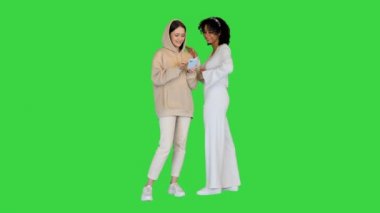 İki genç kız yeşil ekranda akıllı telefon kullanarak gülümsüyor, Chroma Key.