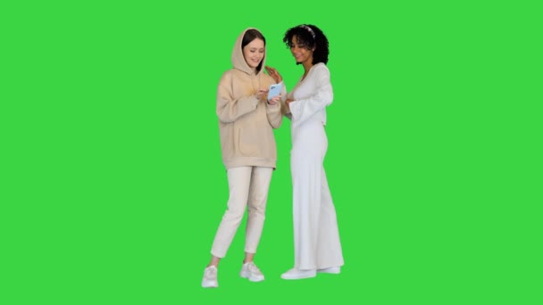 Duas meninas sorrindo usando telefone inteligente em uma tela verde, Chroma Key. — Vídeo de Stock