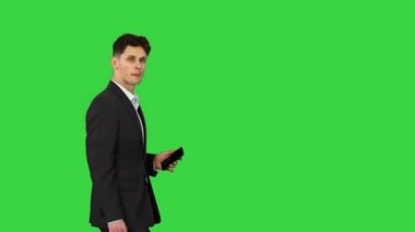 Elinde telefon, elinde evrak çantasıyla yeşil ekran Chroma Key 'e bakan yakışıklı ve şüpheli bir işadamı..