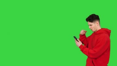 Yakışıklı, sıradan bir adam, akıllı telefonuyla müzik dinliyor ve yeşil ekranda yürürken dans ediyor, Chroma Key.