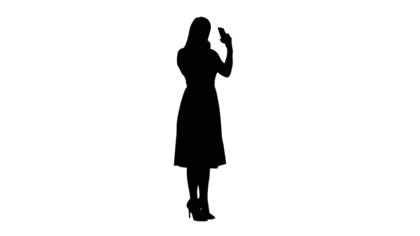 Silhouette Frau, die Lippenstift aufträgt und auf ihr Handy schaut. — Stockfoto