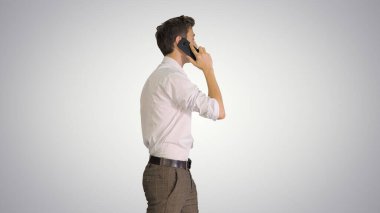 Yakışıklı bir adam gradyan sırtında yürürken telefonla konuşuyor.