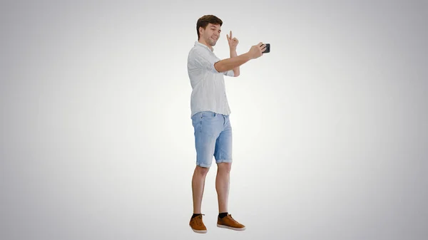 Tânăr în cămașă albă casual luând selfie-uri pe telefonul său pe g — Fotografie, imagine de stoc
