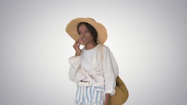 Piękna młoda Afroamerykanka w słomkowym kapeluszu rozmawiająca przez telefon na gradientowym tle. — Wideo stockowe