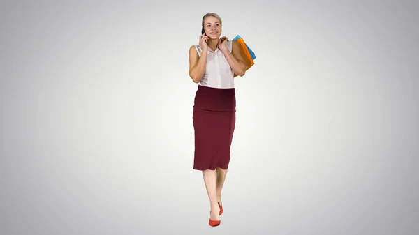 Shopping femme avec des sacs parler au téléphone sur gradient backgr — Photo