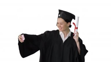Diploması olan mutlu bir bayan mezun ve beyaz arka planda telefonuyla selfie çekiyor..