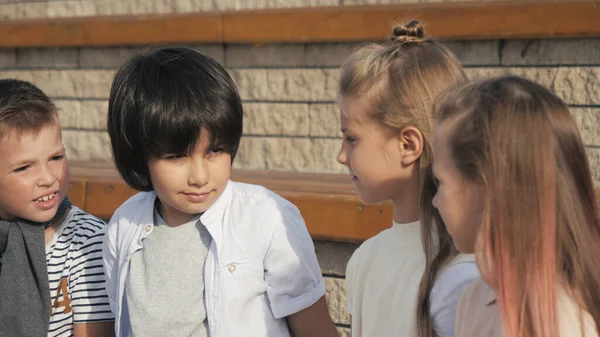 Diverse groep kinderen zitten op een bank samen te wachten. — Stockfoto