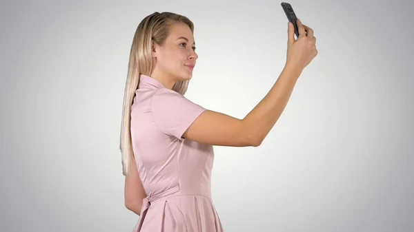 Young beautiful woman makes selfie on her phone on gradient back — Stock Photo, Image