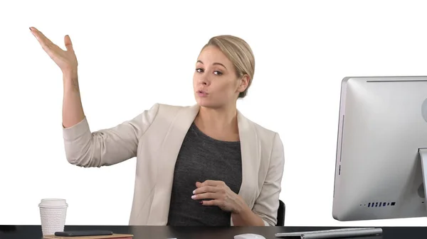 Señora mirando y hablando con la cámara en su escritorio y señalando — Foto de Stock