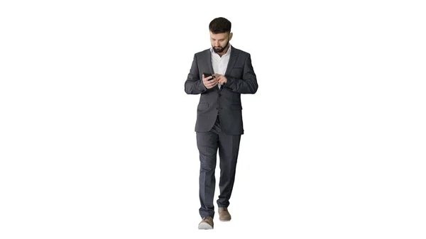Бизнесмен ходит и пользуется телефоном на белом фоне. — стоковое фото