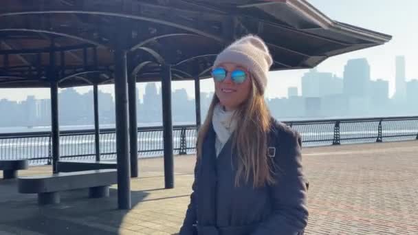 Een jong meisje loopt langs de pier op een zonnige koude dag — Stockvideo