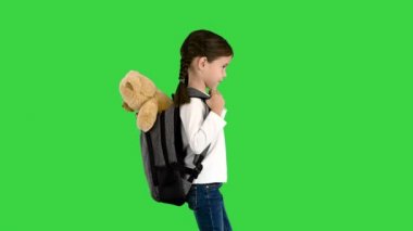 Okula giderken yeşil ekranda sırtında oyuncak ayısıyla dolaşan tatlı küçük bir kız, Chroma Key..
