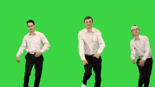 白いシャツを着た3人の笑顔の男が緑の画面でカメラを見て同期ダンスルーチンをやっている、クロマキー. — ストック動画