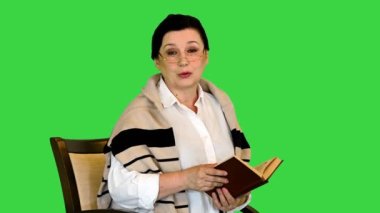 Yeşil Ekran 'da, Chroma Key' de yüksek sesle kitap okuyan son sınıf öğrencisi bir kadın..