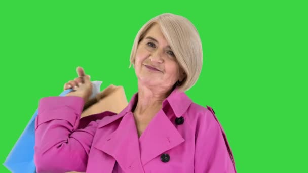Красива старша жінка у плащі з сумками на зеленому екрані, Chroma Key. — стокове відео