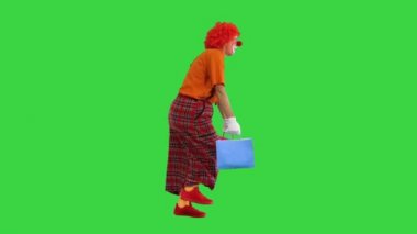 Ağır alışveriş torbalarıyla komik bir palyaço Yeşil Ekran üzerinde yürüyor, Chroma Key.