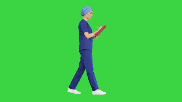 Médico profesional femenino haciendo notas en el diario médico mientras camina en una pantalla verde, Chroma Key. — Vídeos de Stock