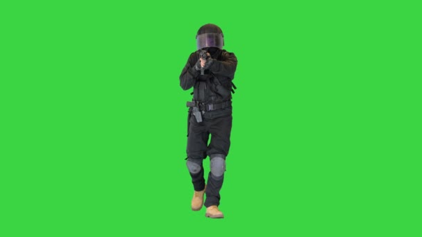 Maskiertes Mitglied der bewaffneten SWAT-Polizei zu Fuß und mit einem Gewehr auf einem grünen Bildschirm, Chroma Key. — Stockvideo
