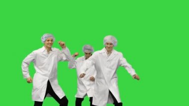 Beyaz cüppeli ve koruyucu şapkalı üç erkek doktor çerçevede koşuyor ve yeşil ekranda aptalca dans etmeye başlıyor..