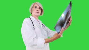 Kıdemli kadın doktor florografiyi inceliyor ve sadece yeşil ekran Chroma Key 'e bakıyor..