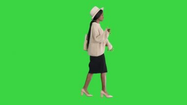 Yeşil Ekran 'da yürürken örgü ve beyaz şapkalı şık Afro-Amerikan kadın, Chroma Key..