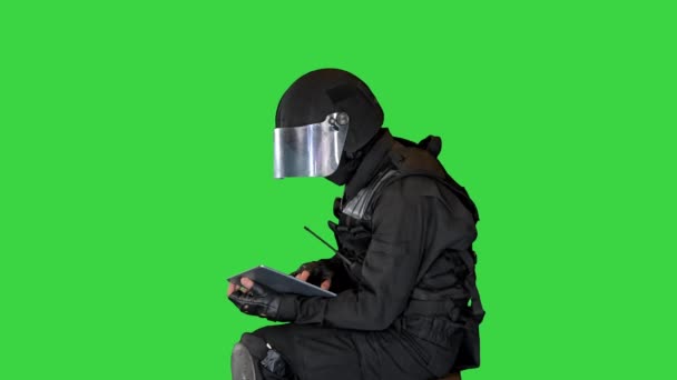 Officier de l'équipe SWAT assis et utilisant une tablette numérique sur un écran vert, Chroma Key. — Video