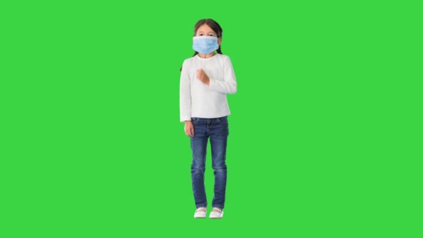 Niña con mascarilla protectora respirando profundamente mirando la cámara en una pantalla verde, Chroma Key. — Vídeo de stock