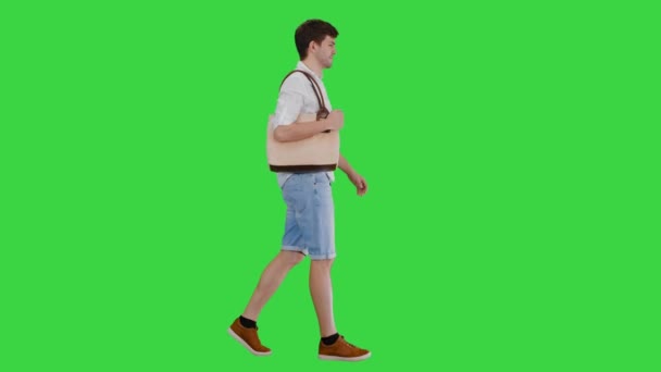 Bonito homem sorridente de camisa branca andando com um saco no ombro em uma tela verde, Chroma Key. — Vídeo de Stock
