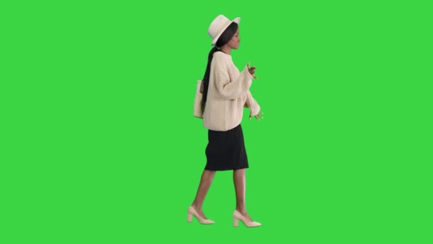 Elegante mujer afroamericana en punto y sombrero blanco bailando mientras camina sobre una pantalla verde, Chroma Key. — Vídeos de Stock
