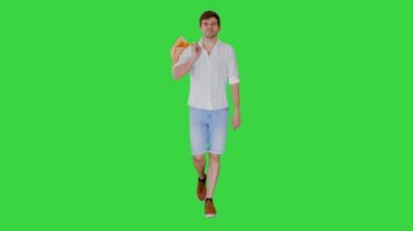 Günlük giysiler içinde yakışıklı bir adam alışveriş çantalarıyla yürüyüp yeşil ekran Chroma Key 'deki kameraya bakıyor..