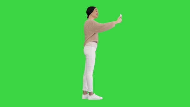 Sonriente joven que tiene videollamada en su teléfono saludando la mano en una pantalla verde, Chroma Key. — Vídeos de Stock