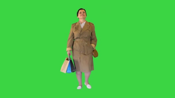 Donna bruna matura in un cappotto con borse della spesa che camminano su uno schermo verde, Chroma Key. — Video Stock