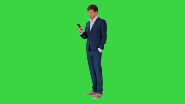 緑の画面で彼の携帯電話を見て深刻なビジネスマン,クロマキー. — ストック動画