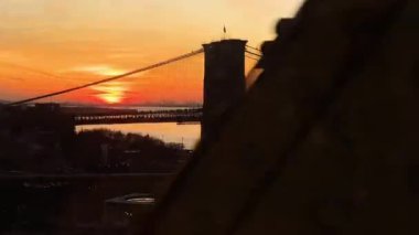Gün batımında Brooklyn Köprüsü, Manhattan Köprüsü 'nden geçen trenden görüntü.