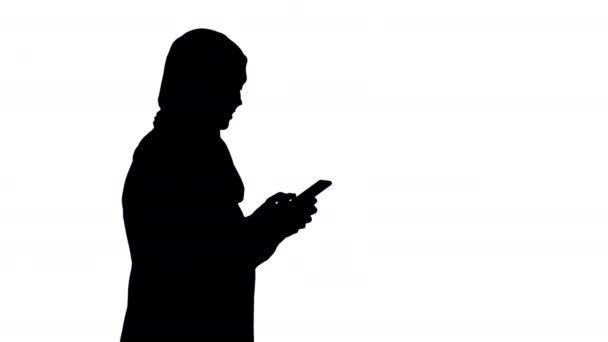 Silhouet Moslim vrouw berichten op haar mobiele telefoon tijdens het lopen. — Stockvideo