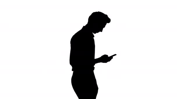 Silhouet Man in wit shirt loopt met behulp van mobiele telefoon. — Stockvideo