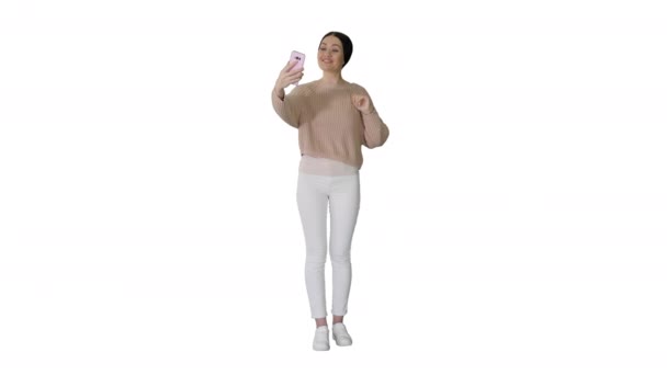 Lächelnde junge Frau mit Videoanruf auf ihrem Handy, winkende Hand auf weißem Hintergrund. — Stockvideo