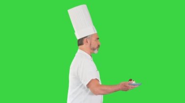 Erkek pasta şefi elinde tatlıyla hızlı yürüyor. Yeşil ekranda, Chroma Key..