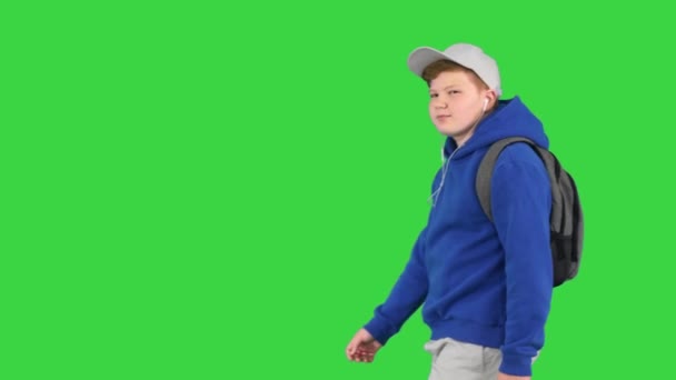 緑の画面、クロマキーの音楽を聞いている間にハンサムな男の子が歩いている. — ストック動画