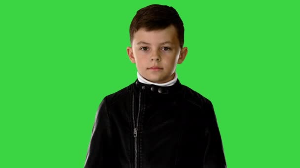 Крутой молодой парень в кожаной куртке надевает черные очки с руками на бедрах на зеленый экран, хрома ключ. — стоковое видео