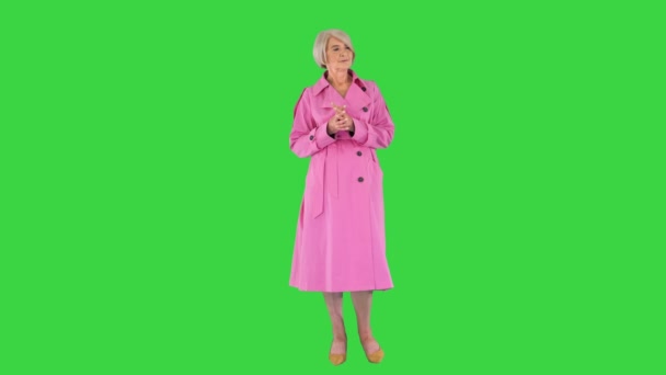 Señora inteligente en gabardina rosa de pie, esperando y pensando en una pantalla verde, Chroma Key. — Vídeo de stock