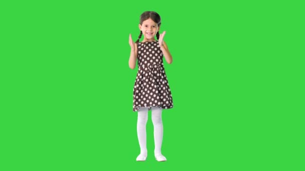 Sonriente niña en vestido de lunares aplaudiendo sus manos vigorosamente mirando a la cámara en una pantalla verde, Chroma Key. — Vídeo de stock