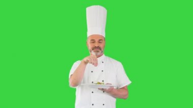 Şef salatasını süslüyor ve yeşil ekranda gülümseyen kameraya bakıyor, Chroma Key.