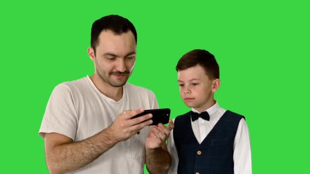 Happy father and son watching something on the phone and smiling on a Green Screen, Chroma Key. — Stock Video