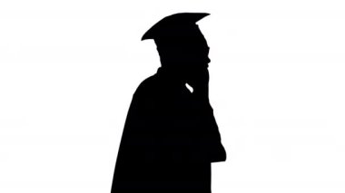 Siluet gülümseyen Afro-Amerikan erkek öğrenci mezuniyet cübbesi içinde yürürken telefonda konuşuyor..