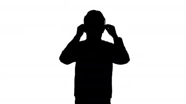 Silhouette Fiatal fiú bőrdzsekiben fekete szemüveget visel, karokkal a csípőjén.. — Stock videók